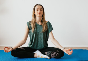 Seseorang duduk bersila meditasi di ruangan tenang