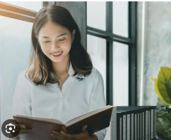 Seseorang membaca buku di meja dengan cahaya alami